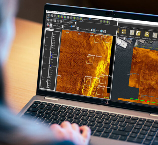 Person analyzing thermal imaging data on a laptop, with orange heat-map screens and seebyte branding visible on the interface.