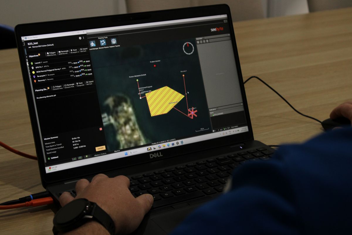 Hands on a Dell laptop displaying a multi-panel data visualization dashboard with a yellow polygon and red connection lines on screen